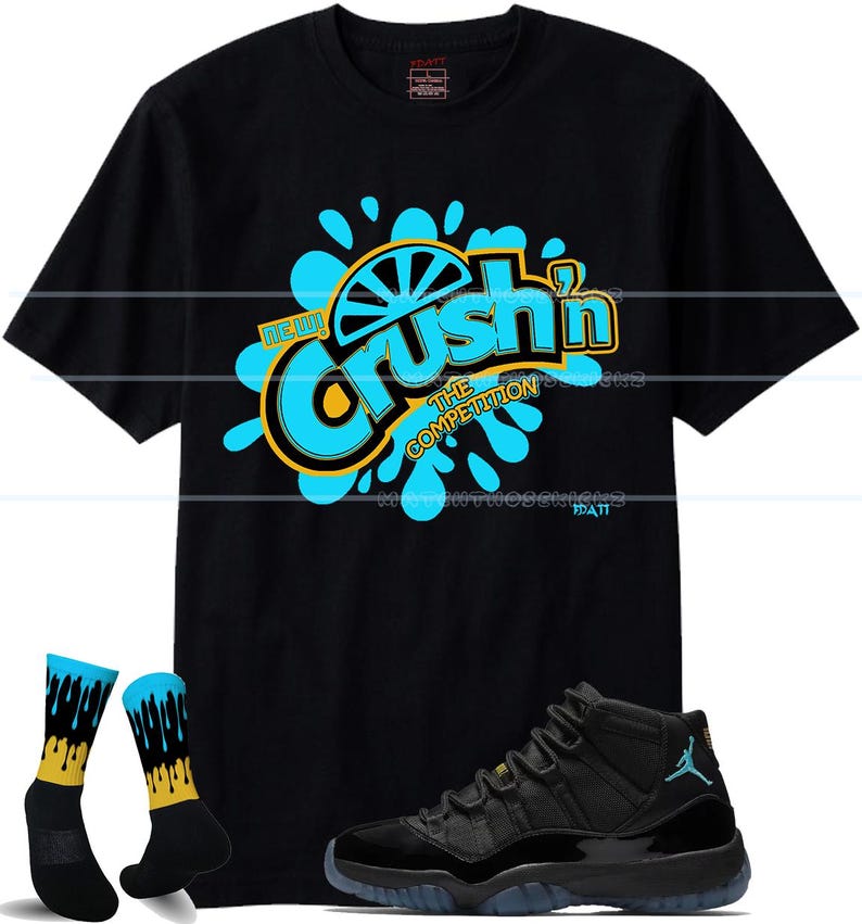 Puede incluir: Camiseta negra con un gr&aacute;fico que dice "Crush'n The Competition" en azul y amarillo. La imagen tambi&eacute;n incluye zapatillas negras con suela azul y un par de calcetines negros con detalles azules y amarillos.