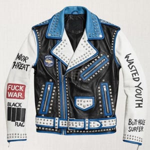 Puede incluir: Chaqueta de cuero negra con mangas blancas y detalles azules. La chaqueta presenta tachuelas plateadas, cremalleras y un cinturón. El texto en las mangas dice "MOR THREAT", "FUCK WAR", "BLACK FLAG", "WASTED YOUTH" y "BUTTHOLE SURFER".