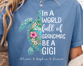 May include: Blue jean t-shirt with a sea turtle design. The turtle is half turquoise and half floral with the text "In A World Full of Grandmas Be A Gigi". Names Oliver, Sophia, and Leonor are below the text.