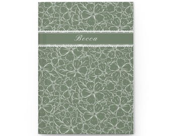 May include: A journal with a floral pattern in white on a sage green background. The word "Becca" is printed in white on a sage green horizontal band across the center of the journal.