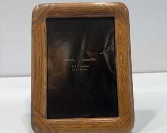 May include: A rectangular wooden picture frame with rounded corners and a visible grain pattern. The black insert features the gold text: wood... naturally, 5 x 7 inches, 13 x 18 cms. The frame has a smooth, polished finish and a sturdy construction.
