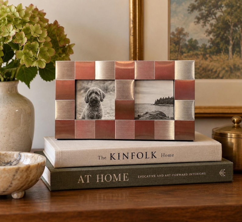 May include: A rectangular double photo frame featuring a checkerboard pattern of alternating brushed silver and copper-toned metal squares. The frame holds two black and white photographs, one showing a dog and the other a coastal landscape scene.