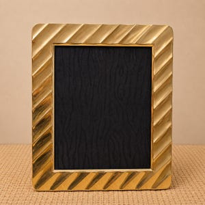 May include: A rectangular picture frame with a metallic gold finish and a diagonal ribbed texture along the border. The frame features a solid black rectangular insert in the centre, providing a high-contrast look for displaying photographs or art.