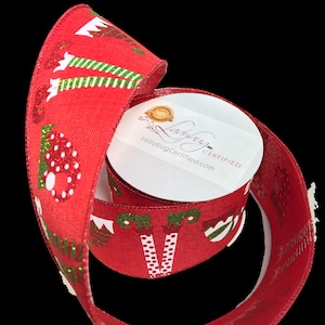 May include: Red Christmas ribbon with a festive pattern of elves, mushrooms, and trees. The ribbon is rolled, revealing a white label with the text "ladybugcertified.com". The ribbon is suitable for holiday crafts and gift wrapping.
