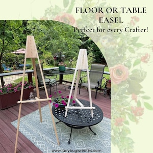 May include: Two wooden easels, one tall and one shorter, stand on a wooden deck. The easels are made of natural wood and have a simple design. The taller easel is in the foreground and the shorter easel is in the background. The easels are on a wooden deck with a rug underneath. The text "FLOOR OR TABLE EASEL Perfect for every Crafter!" is at the top of the image. The text "www.ladybugwreaths.com" is at the bottom of the image.