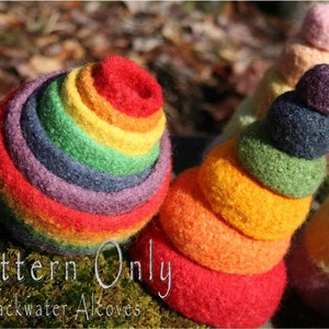 Puede incluir: Un juguete de apilar de fieltro de color arcoíris con un patrón de círculos concéntricos. El juguete está hecho de fieltro suave y colorido y es perfecto para que los niños jueguen.