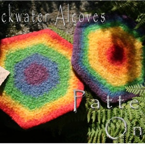 May include: Two rainbow-colored crocheted coasters with a hexagonal shape. The coasters are made with a fuzzy yarn and have a multi-colored concentric circle design. The text "Blackwater Alcoves" is written in white on a dark background above the coasters. The text "Pattern Only" is written in white on a green background below the coasters.