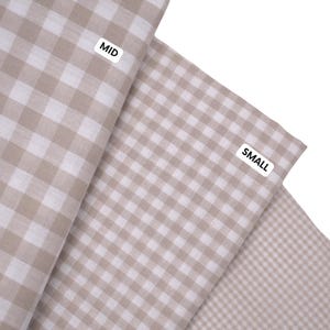 May include: Three pieces of fabric featuring a beige and white gingham check pattern. Each piece is labeled with a white tag containing black text: MID for the largest check, SMALL for the medium check, and MINI for the smallest check pattern.