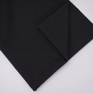 May include: A solid black fabric piece folded at one corner to reveal the texture and depth of the material. The textile features a smooth, matte finish with clean, straight edges and a consistent, deep black color throughout the entire surface.
