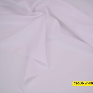 May include: A solid, opaque, cloud white fabric featuring a smooth, matte texture. The material is draped in soft, flowing folds that create subtle shadows and highlights across the surface. The text CLOUD WHITE is printed in a yellow box.