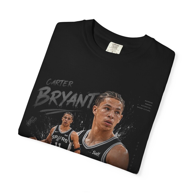 May include: Black t-shirt featuring a graphic of basketball player Carter Bryant. The design includes his name in a stylized font and a portrait of him in a basketball uniform. The shirt also has the words "Defense, Energy, Potential, Squad Future."