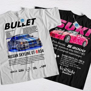 Può includere: Due magliette grafiche. Una maglietta bianca presenta un design di auto Nissan Skyline GT-RR34 blu e argento con la scritta "BULLET". L'altra maglietta nera mostra un design di auto Honda S2000 rosa con la scritta "SUKI".