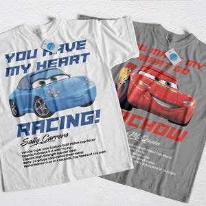 Puede incluir: Dos camisetas, una blanca y otra gris, con gráficos de coches de dibujos animados. La camiseta blanca muestra un coche azul con el texto "YOU HAVE MY HEART RACING!" y "Sally Carrera". La camiseta gris muestra un coche rojo con "YOU MAKE MY HEART GO CHOW!" y "McQueen."