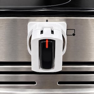 May include: A white plastic stove knob cover featuring a rectangular black center insert with a vertical orange indicator line. The cover is mounted on a stainless steel oven control panel with a black graphic icon of a square and a dot.