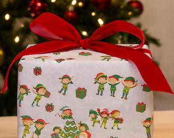 Peut inclure: Un coffret cadeau emballé avec un nœud en velours rouge. Le papier d'emballage est gris clair avec un motif d'elfes de Noël, de sapins de Noël et de cadeaux emballés. L'arrière-plan présente un sapin de Noël.