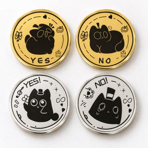 May include: Four circular metal coins featuring black cat illustrations. Two coins are gold-toned with YES and NO text, while two are silver-toned with YES! and NO! text. Each coin displays a stylized cat character, small hearts, and icons.