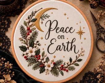 May include: A circular wooden embroidery hoop containing white fabric with the stitched text Peace on Earth. The design features a gold crescent moon, small gold stars, and a wreath of green pine needles, white flowers, and red berries.