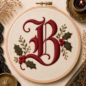 Peut inclure: Un tambour à broder circulaire en bois contenant un panneau de tissu crème. Le tissu présente une grande lettre B brodée en rouge foncé orné, entourée de feuilles de houx vertes détaillées, de baies rouges et de petits accents crème.