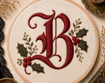 May include: A circular wooden embroidery hoop containing a cream-colored fabric panel. The fabric features a large, ornate, deep red embroidered letter B, surrounded by detailed green holly leaves, red berries, and small cream-colored accents.
