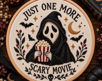 May include: A circular embroidery hoop featuring a black-hooded figure with a white mask holding a red and white striped popcorn bucket. The text reads JUST ONE MORE SCARY MOVIE, surrounded by embroidered bats, a crescent moon, stars, and berries.