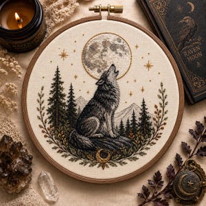 May include: A circular embroidery hoop featuring a detailed needlework scene of a grey wolf howling at a full moon. The design includes dark green pine trees, mountain silhouettes, golden stars, and a crescent moon accent on a cream fabric background.