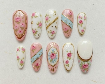 Unhas postiças vintage com estampa floral rosa e moldura dourada, feitas à mão, longas e elegantes, em formato amendoado.