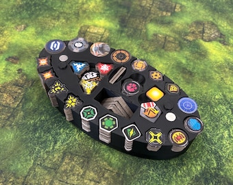 May include: Black oval-shaped game token organizer with various colorful game tokens. The organizer has multiple compartments to hold the tokens. The tokens have different shapes and designs, including geometric shapes and symbols.