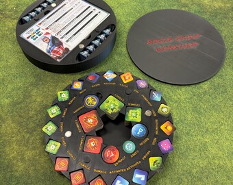 May include: A black board game organizer with a circular design. The organizer includes a lid with the text "ROGUE GROVE WORKSHOP" and a central rotating piece with various game tokens. The tokens are in various colors and shapes.
