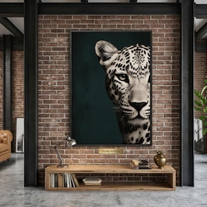 May include: A framed art print featuring a close-up of a leopard's face, with black spots on a white and tan coat. The artwork is set against a dark teal background, creating a striking contrast. The print is displayed in a modern interior setting.