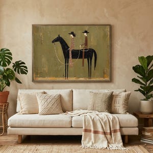 May include: A framed artwork depicts a black horse with two riders in hats. The riders are wearing patterned clothing. The artwork hangs above a cream-colored sofa with decorative pillows and a throw blanket. A potted plant and a side table are also visible.