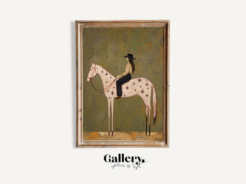 May include: A framed wall art print featuring a painting of a person in a black hat, tan shirt, and dark pants riding a white horse with a star pattern. The horse has a red bridle and stands against a textured olive green background.