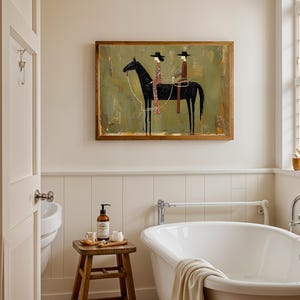 May include: A bathroom scene featuring a clawfoot tub, a wooden stool with toiletries, and a framed artwork. The artwork depicts two figures on a black horse against a green and gold background. The room has a neutral color palette.