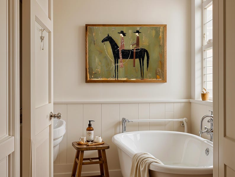 May include: A bathroom scene featuring a clawfoot tub, a wooden stool with toiletries, and a framed artwork. The artwork depicts two figures on a black horse against a green and gold background. The room has a neutral color palette.