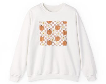 May include: White crewneck sweatshirt featuring a square pattern of orange pumpkins and white flowers on a checkered background. The pumpkins have a classic shape and are set against a light brown and white checkered pattern.