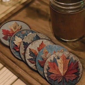 Può includere: Set di sei sottobicchieri rotondi con un design a foglia autunnale. Ogni sottobicchiere presenta una foglia diversa con sfumature di rosso, arancione, giallo e marrone. I sottobicchieri sono disposti su un vassoio di legno.