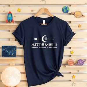 May include: A white ceramic mug with a black handle and the text "But First, Coffee" in a bold, black font. The mug is set against a blurred background, suggesting a cozy setting. The mug appears to be approximately 4 inches tall.