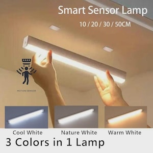 May include: A smart sensor lamp with the text "Smart Sensor Lamp" and "10/20/30/50CM". The lamp is held by hands and has three colour options: cool white, nature white, and warm white. The text "3 Colors in 1 Lamp" is also present.