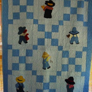 May include: A handmade quilt with a light blue and white checkered pattern. The quilt features appliqued figures of people wearing hats and overalls. The figures are in various colors, including black, yellow, and blue. The quilt has a blue border.
