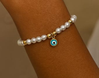 Pulsera de perla con dije de ojo malvado: joyería de protección en tonos dorados