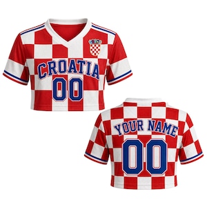 May include: A red and white checkered crop top with the word "CROATIA" in blue letters and the number "00". The top has a V-neck and a Croatian coat of arms. The back of the top says "YOUR NAME" and has the number "00".