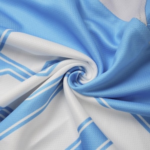May include: Close-up of a light blue and white fabric with a striped pattern. The fabric is tightly woven and has a slight sheen. The light blue sections are solid, while the white sections have thin blue stripes.