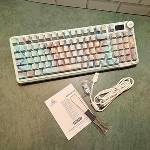 May include: A mechanical keyboard with a marble-patterned keycap design in shades of blue, brown, and white. Includes a white USB cable, a keycap puller, and a product manual. The keyboard has a volume control knob and a small display.