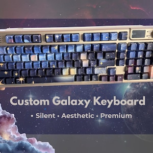 May include: Custom galaxy keyboard with blue and gold keycaps. The keycaps feature a galaxy design with stars and nebulae. The keyboard has a gold-colored frame and a small display screen.