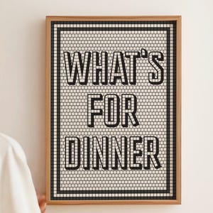 May include: A framed wall art piece with the text "WHAT'S FOR DINNER" in bold, black letters. The background is a mosaic pattern of small white and black tiles, framed by a thin black border and a natural wood frame.