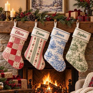 May include: Four personalised Christmas stockings hanging in a row. The first features a red and white patchwork pattern with the name Olivia. The second has a green striped pattern with candy canes and the name Emma. The third shows a blue toile print with the name James. The fourth displays a green toile print with the name Sophia.