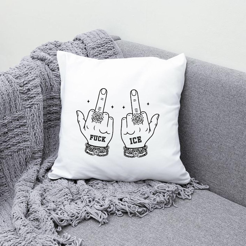 May include: White square pillow with a black graphic of two hands giving the middle finger. The word "FUCK" is printed below one hand, and "ICE" below the other. The hands wear rings and bracelets.