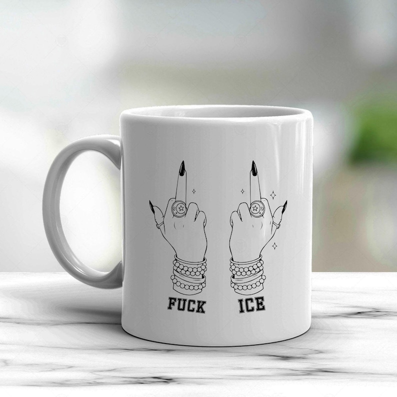 May include: White ceramic mug featuring a black and white illustration of two hands giving the middle finger. The hands are adorned with rings, bracelets, and long black fingernails. The words "FUCK ICE" are printed below the hands.