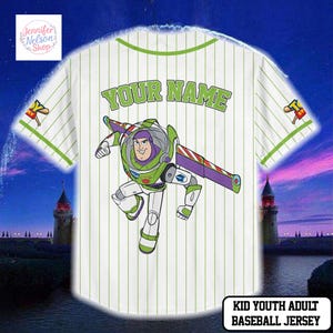 A white baseball jersey with a cartoon character printed on it, featuring a character from the Toy Story franchise. The jersey has a green stripe and the text "YOUR NAME" is displayed on the back.