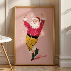 Könnte beinhalten: Ein gerahmter Druck eines tanzenden Weihnachtsmanns. Er ist in einem rosa Mantel, einer gelben Hose mit Tupfen und einem roten Hut dargestellt. Der Hintergrund ist ein zartes Rosa und der Rahmen ist goldfarben. Das Kunstwerk wird neben einem weißen Stuhl ausgestellt.