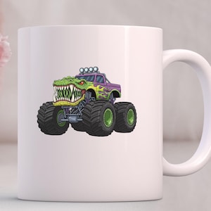 Puede incluir: Taza de cer&aacute;mica blanca con un dibujo de un monster truck con cabeza de cocodrilo verde, carrocer&iacute;a morada y llamas verdes y amarillas. El cami&oacute;n tiene neum&aacute;ticos negros grandes.